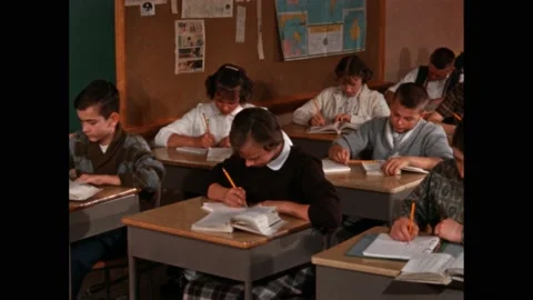 1960s: girl does maths work at desk in silent classroom. Children in classroom 스톡 동영상 219965704