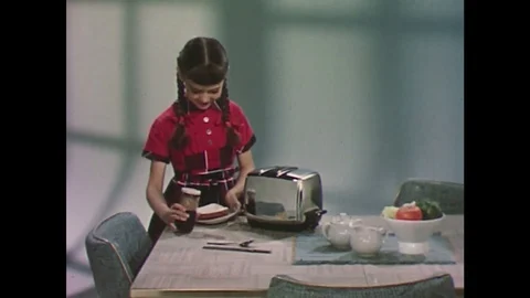 1960s: Girl puts bread in toaster, looks at camera and waves hands. Stock Footage