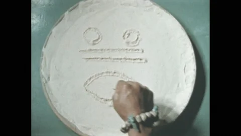 1960s: Hand traces face pattern into white powder. Exterior Mayan temple Chichen Stock Footage 195118134