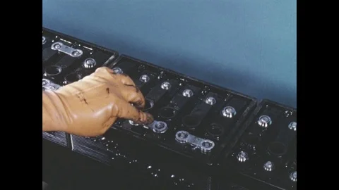 1960s: Hands fit metal objects on box. Hands melt metal objects to box Stock Footage