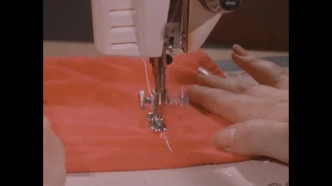 1960s: Hands pulling material through sewing machine. Stock Footage 248081815