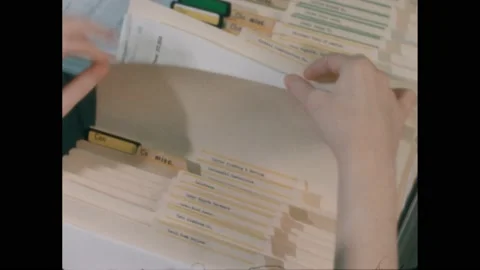 1960s: Hands sort through open filing cabinet drawer. Hands place index card Stock Footage 222956458