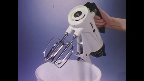 1960s: Hands take beaters out of electric mixer / Animated man slices off piece Stock Footage