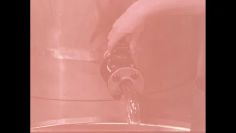 1960s: Hands turn knobs on tanks above churning tank of liquid. Worker pours 스톡 동영상 251002612