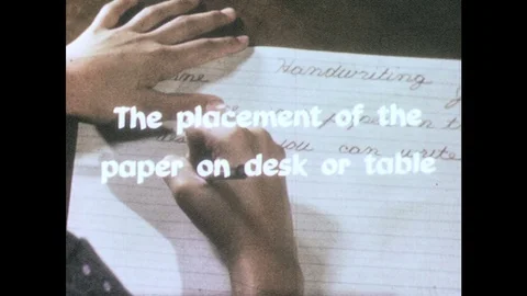 1960s: hands write cursive words on lined paper on desktop in school classroom. Stock Footage 82705651
