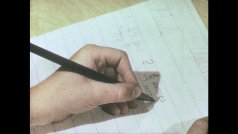 1960s: hands write out math problem and words on ruled paper on desktop in Stock Footage 82705618