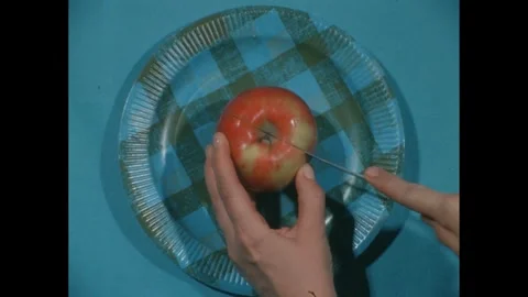 1960s: High angle, apple on plate, hands slice apple in half, give away apple. Stock Footage 271091524