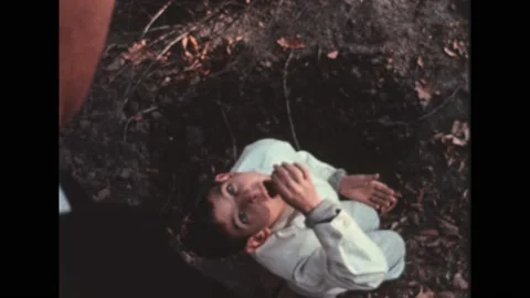 1960s: High angle, boy on ground, leans back to eat worm. Low angle of police Stock Footage 194464776