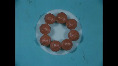 1960s: High angle of cupcakes on plate, hand takes cupcake. Stock Footage 271091472