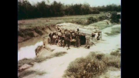 1960s: High angle shot, soldiers by bunker / Soldiers inspect guns. Stock Footage