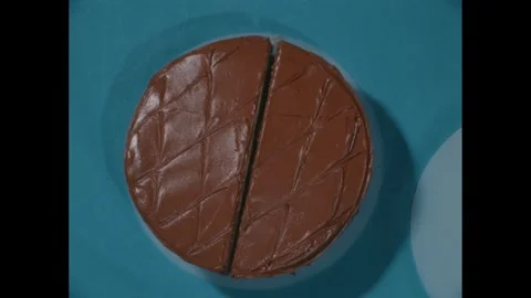 1960s: High angle view of cake, hand slicing cake with knife, hands move half of Stock Footage 271091546