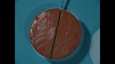1960s: High angle view of cake, hand slicing cake with knife, hands move half of Stock Footage 271091548
