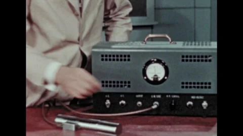 1960s: In lab, man adjusts knobs on machine. He removes wristwatch and holds it 스톡 동영상 278054849