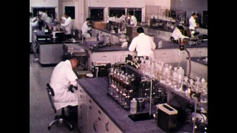 1960s: Large chemistry lab, scientists in white lab coats work at benches. 動画素材 99052022