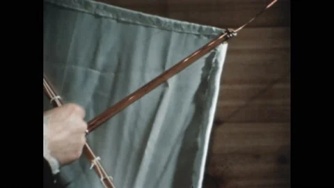 1960s: Lightning in the sky. Hands examine a kite with metal crossbars. Kite Stock Footage 189933780