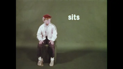 1960s: List of words is categorized as "NAMING WORDS."  Boy leans against pole.  Stock Footage 311772487