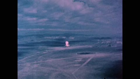 1960s: Looking down on desert, atomic bomb explodes, mushroom cloud rises in 스톡 동영상 159489688