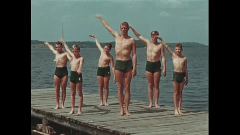1960s: Low angle, boys practicing swimming stroke. Boys on pier doing stroke. Stock Footage 256051612
