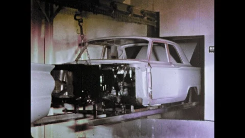 1960s: Machine moves car frame in factory. Man buffing side of car. Stock Footage 103558787