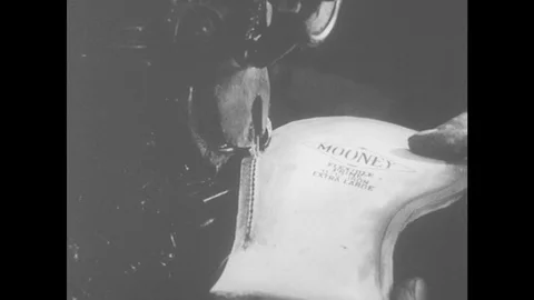 1960s: Machine stitches sole of shoe. Hand holds shoe at sewing machine Stock Footage