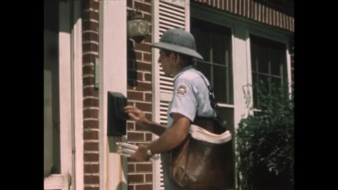 1960s: mailman in pith helmet with leather bag sorts letters on porch in front Stock Footage 245820247