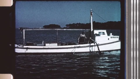 1960s: Man on boat pulls role, raising boat's crane-arm and attached net from Stock Footage