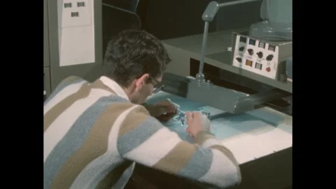1960s: A man diligently focuses on assembling small electronic components in a Stock Footage 295140654