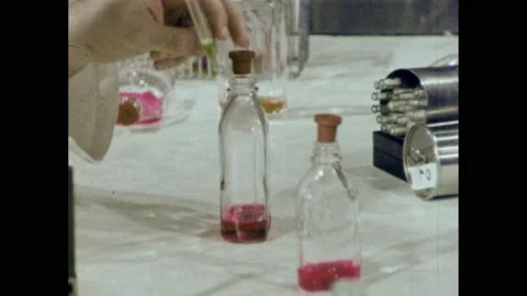 1960s: Man dropping liquid into vials, zoom in. Hand put vials in refrigerator. Stock Footage 149643196
