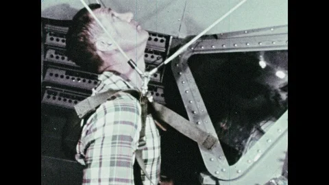 1960s: Man in flight simulator looks up. Simulators dock with each other. Stock Footage 100302714