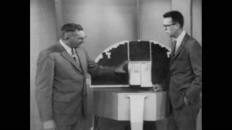 1960s: Man gestures at orbiting solar observatory and speaks. Stock Footage 145210268