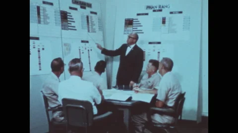 1960s: Man gestures with pointer and speaks. Men seated at table look up. Men Video stock 143366725