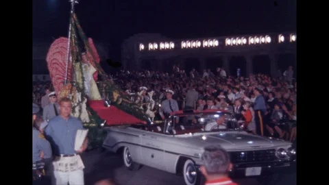 1960s: Man holding printed program walks in parade. Woman waves from parade Video stock 109243278