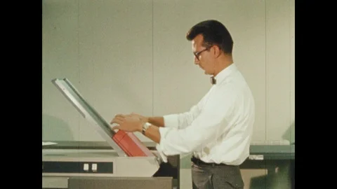 1960s: Man loads papers into machine. Man checks printer. Computer reels spin. Stock Footage 111285368