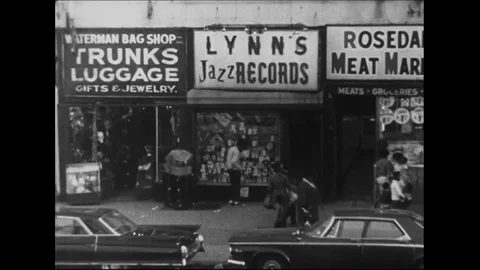 1960s - A man looks in a store window and lights a cigarette in an urban area. Stock Footage 84333936