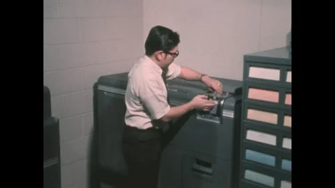 1960s: Man opens card printer and looks inside. 動画素材 276504425