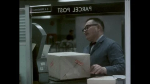 1960s: man at "Parcel Post" window takes package wrapped in brown paper, weighs Stock Footage 240675698