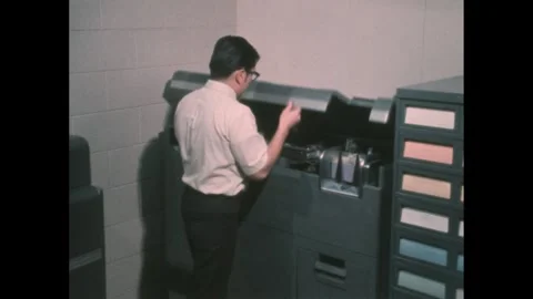 1960s: Man presses button on programming card printer. Printer begins working. 動画素材 276504420