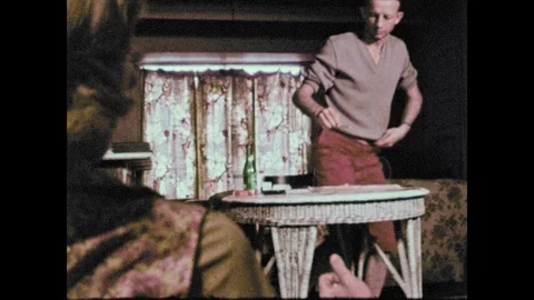 1960s: Man removes drawstring from pants and ties it around boy's arm. Man Video stock 129975577