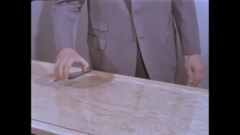 1960s: Man slides rectangle shaped piece of glass over large sheet of glass. Stock Footage 295292368