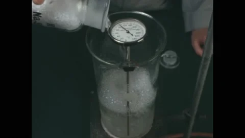 1960s: Man stands in front of beaker with boiling liquid. Man shakes white Stock Footage 172028652