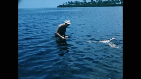 Men standing in waist-deep water, with fishing spears - Digital Collections  - Northwestern University Libraries