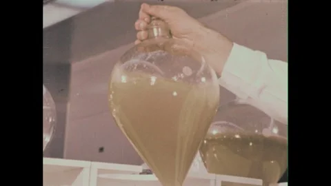 1960s: Man talking, pan to man at microscope. Magnified view of drug. Man in lab Stock Footage 243582325