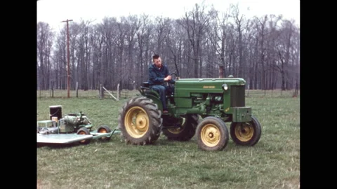 1960s: man on tractor pulling a pallet with objects stacked on large paper sheet Stock Footage 132616172
