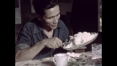 1960s: Man uses spoon to put rice on plate.  Woman puts plate on table.  Woman Stock Footage 289920041