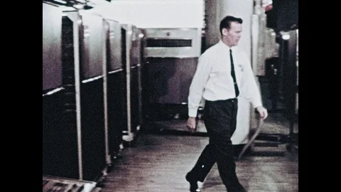 1960s: Man walks through NASA server room and sits at mission control console. Видео 101404018