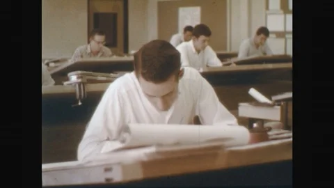 1960s: man writes at architect desk in office with men. man looks around. Stock Footage 75937962