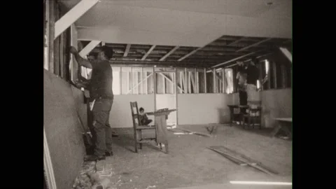 1960s: Men construct room, hang sheetrock on wall frames, hammer nails. Men Stock Footage 213949484