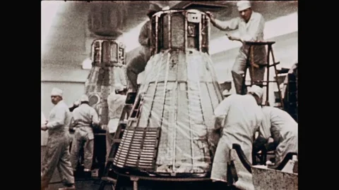 1960s: Men constructing on rocket capsules. Man puts panel on engine. Men push Stock Footage 109216549