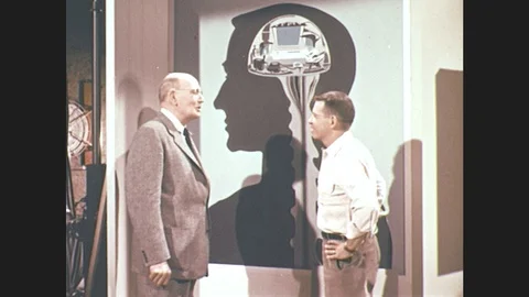 1960s: men leave map of human head. men walk up to man at desk and talk. man Stock Footage