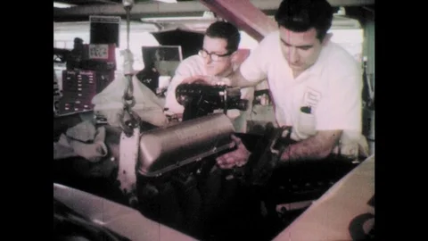 1960s: Men lower engine into car.  Men look down and work on cars. Stock Footage 77452059